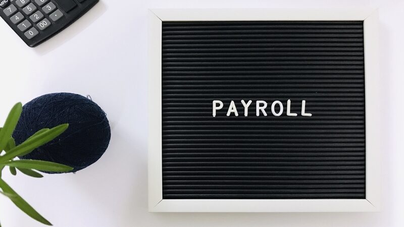 payroll sign board and calculator on white backgro AUG4PHM